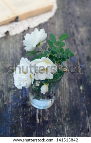 Dog rose flowers in a glass on rusted garden table
