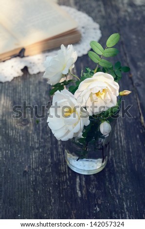 Dog rose flowers in a glass on rusted garden table