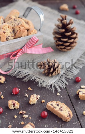 Cranberry biscotti in decorative crate on linen napkin on rusted wooden table with selective focus on foreground