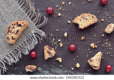 Crumbled biscotti and fresh winter cranberry on dark wooden background
