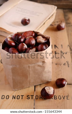 Chestnut in paper bag and vintage book on rustic background