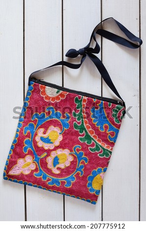 Handbag with suzani embroidery over white wooden background