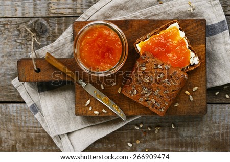 Rye bread sandwich  with butter and apricot jam on cutting board, table top shot