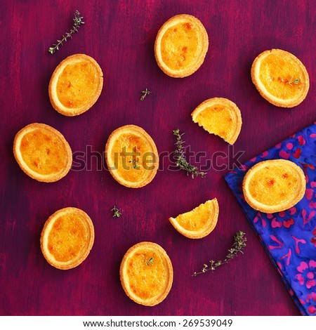 Mini lemon tarts with thyme on deep lilac background