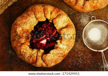Just baked homemade open pies or galette with apples and berry mix, topped with sugar on baking paper