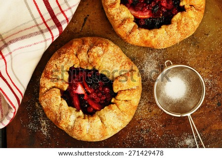 Just baked crusty galette with apples and berries topping with sugar on baking sheet