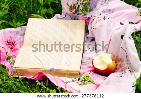 Picnic at summer meadow - eating apple and reading book