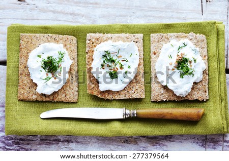 Rye loaves sandwich with homemade cottage cheese spread with coriander and chopped dill on green table napkin