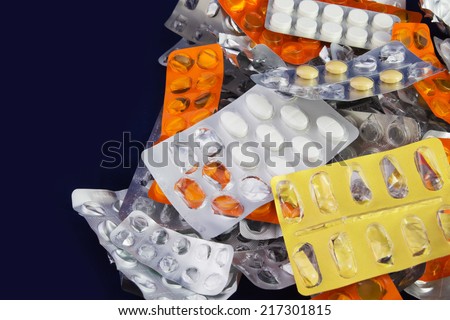 Tablets and Pills in Blister and Many Empty Pill Blister Packages. Isolated on a Blue Background.