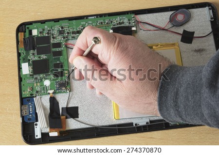 Process of PC Tablet Device Repair on a Wooden Table.