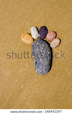 Foot shape by stone in sand