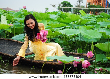 HANOI, VIETNAM, JUNE 12: Unidentified Vietnamese girl wear Ao dai and sit on boat in lake of lotus on June 12, 2010 in Hanoi, Vietnam. Ao dai is famous traditional custume for woman in VIetnam.