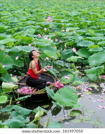 HANOI, VIETNAM, JUNE 15: Unidentified Vietnamese girl wear traditional costume on boat in lake of lotus on June 15, 2012 in Hanoi, Vietnam. Lotus blossom in June or July in VIetnam.