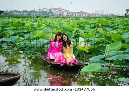 HANOI, VIETNAM, JUNE 12: Unidentified Vietnamese girls wear Ao dai and sit on boat in lake of lotus on June 12, 2010 in Hanoi, Vietnam. Ao dai is famous traditional custume for woman in VIetnam.
