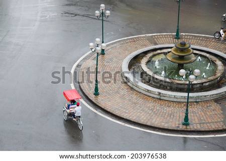 HANOI, VIETNAM, JUNE 28: Cyclos drivers carry tourists in rainy day on June 28, 2014 in Hanoi, Vietnam. Cyclo used to be a popular transportation in Vietnam, it is for tourism now