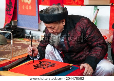 HANOI, VIETNAM, JANUARY 28: Old master is writing ancient letter for everyone in lunar new year on January 28, 2014 in Hanoi, Vietnam. This is a tradition of vietnamese people in lunar new year