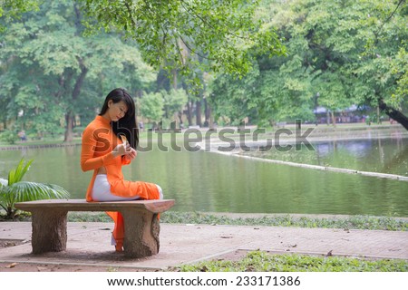 Beautiful vietnamese girl in traditional dress (ao dai) in a park in Hanoi, Vietnam