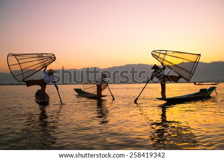 INLE LAKE, MYANMAR - FEB 26: Three fishermen catches fish for food on February 26, 2015 on Inle Lake, Myanmar. Intha people possess the feet-rowing style and the unique fishing equipment.