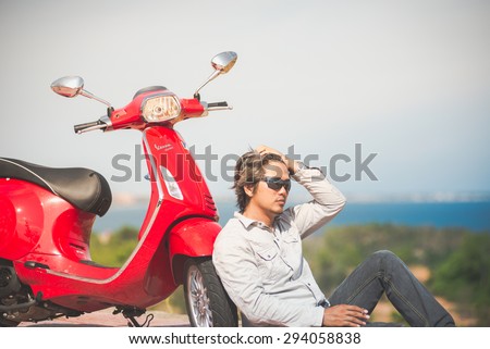 PHANTHIET, VIETNAM - MAY 30 : A man sit near a new Vespa scooter on the beach at May 30, 2014 in Phanthiet, Vietnam