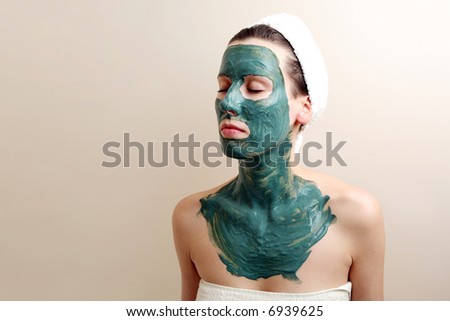 Beautiful young woman with green moisturizing facial cream
