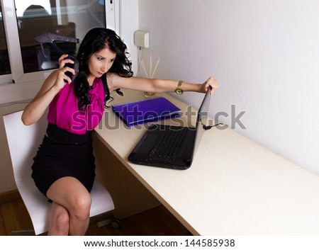 Angry woman destroying laptop, with her heels, at the office.