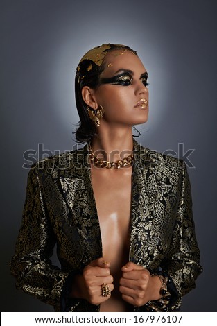 Sexy woman with an amazing ancient egyptian makeup style, black and gold, mystical beauty, icon, gray background.