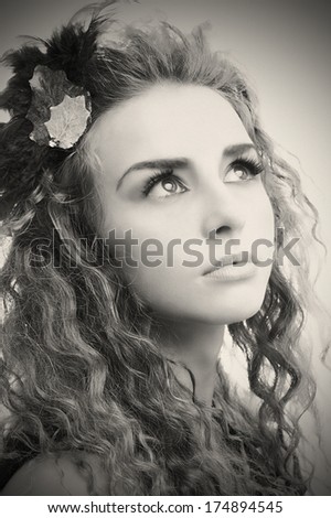 Young stylish teen portrait with artistic make-up and autumn leafs in her hair.Old black and white version.