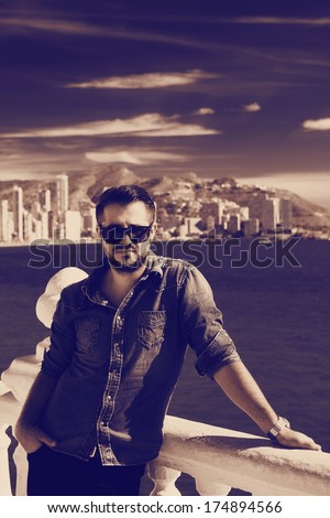 Portrait of trendy guy with beard and sunglasses on a Mediterranean beach, blurred background. Benidorm, Spain. Old black and white version.