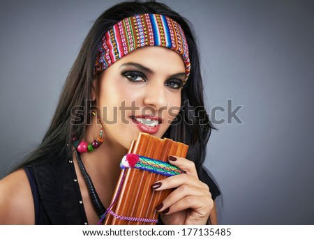 Gorgeous woman portrait with traditional flute and bright smile. Gray background.