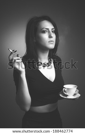 Young businesswoman having a break drinking coffee and smoking a cigarette. Black and white effect.