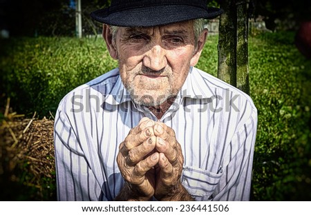 Old man\'s hands, praying in the yard.