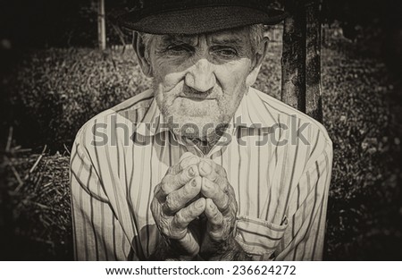 Old man's hands, praying in the yard. Sepia picture.