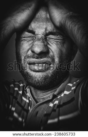 Portrait of a stressed young man with head in hands. Frowning handsome guy having a headache. Old black and white style picture.