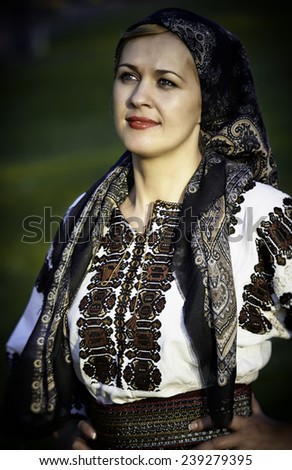 Beautiful woman smiling with hands on hips posing in traditional costume and scarf. Romanian folklore.
