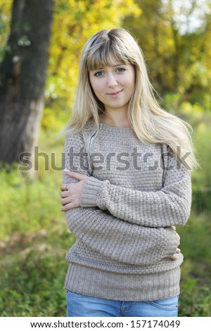 Portrait of young blonde woman in sweater walking  in autumn