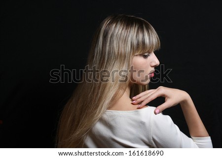 sad blonde woman with  streaked hair in profile black background