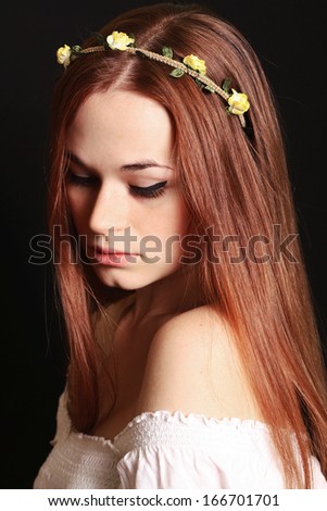 Beautiful red-haired woman with flowers in hair black background