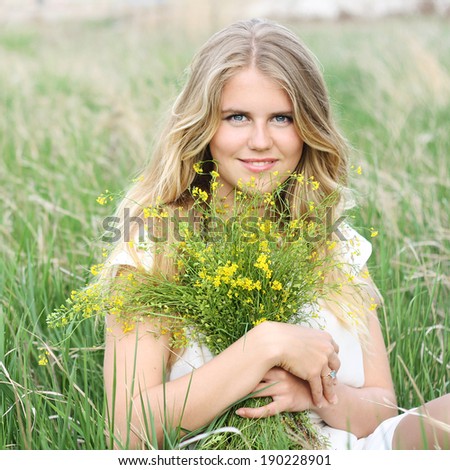 beautiful natural young blonde smiling healthy woman  on field keep in hand yellow flowers warm spring day