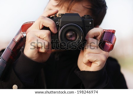 Young man photographer  holding vintage camera with film. outdoor Closeup portrait