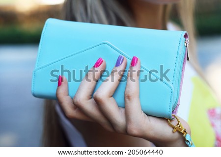 stylish young woman holding blue clutch in hand with pink manicure