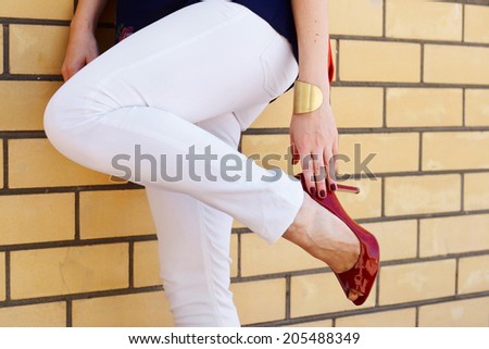 woman legs in high heel shoes outdoor shot near wall , white pants