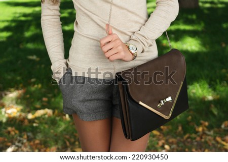 outdoor autumn fashion young trendy girl  with handbag clutch walking
