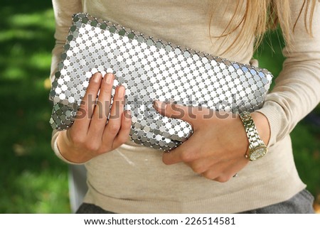 young fashion woman hold silver handbag clutch . stylish accessory young woman hold silver handbag clutch . stylish accessory