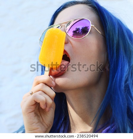 Young  punk girl eating yellow ice cream in summer hot weather in round  pink sunglasses