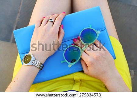 Overhead view of trendy girl accessories blue handbag and green sunglasses . Summer outfit