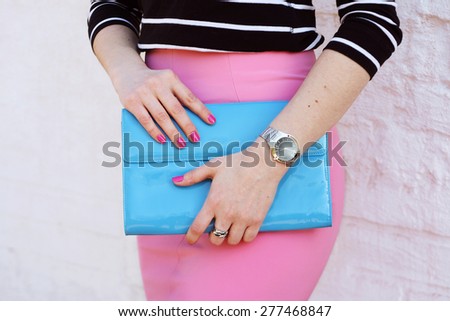 Fashion young woman in pink skirt and black blouse with stylish blue clutch , accessories, watch white background