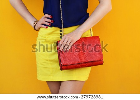 Trendy girl in yellow skirt with red leather bag . Stylish outfit and fashion concept