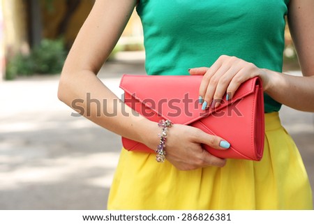 Outdoor summer fashion girl with coral orange handbag clutch . Summer outfit