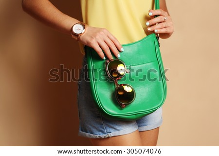 Trendy girl with green handbag clutch and sunglasses , fashion gold watch. Summer spring outfit