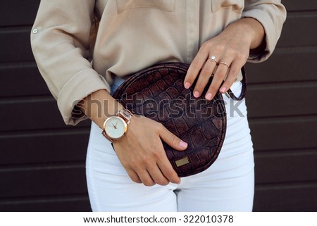 Trendy girl holding small brown leather bag handbag in hand. Stylish accessories